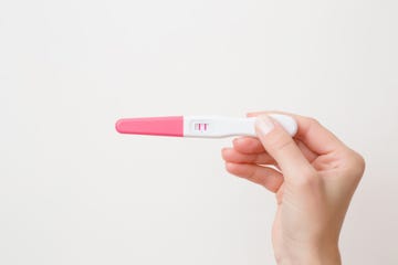 young womans hand holding pregnancy test with a positive result