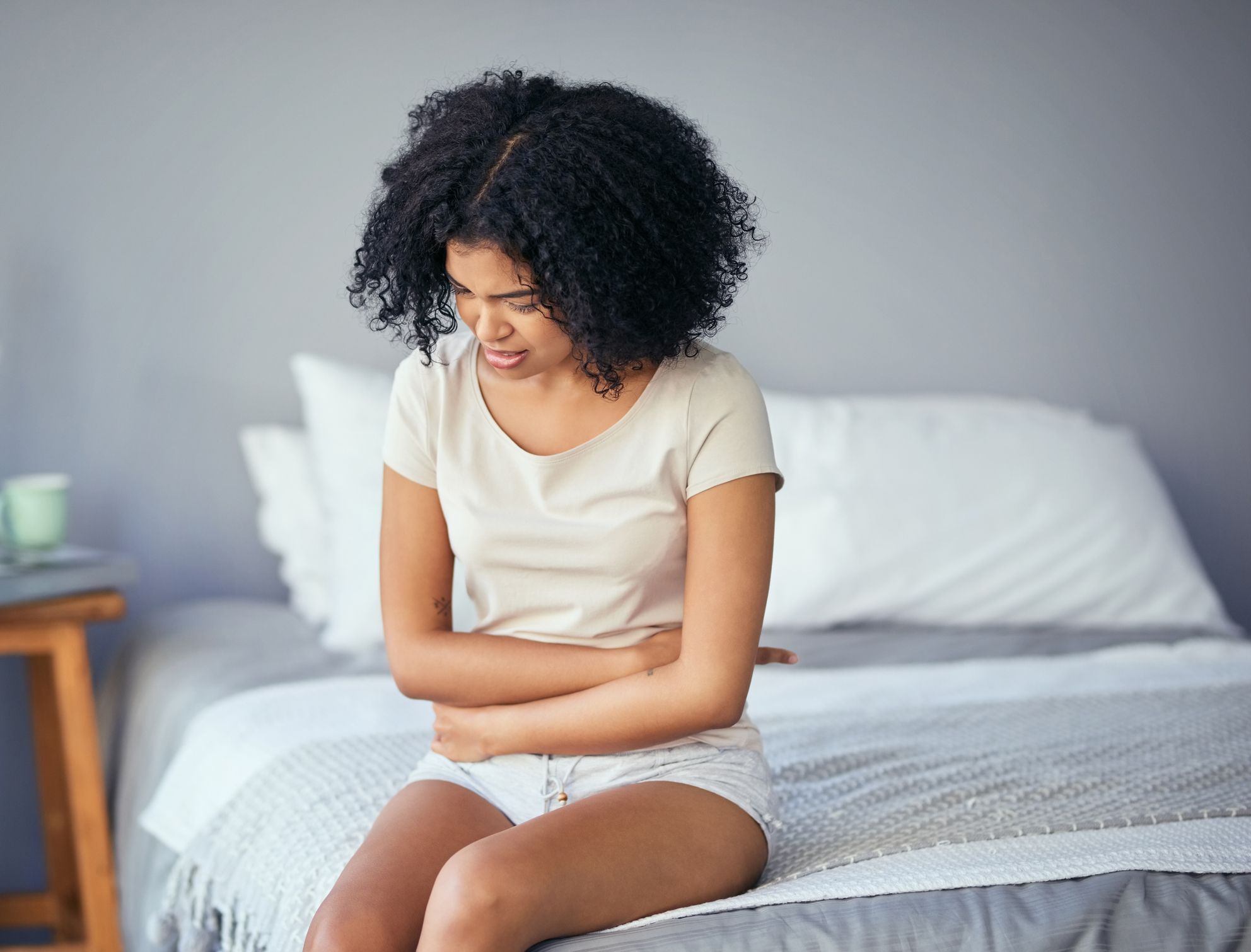 can pcos cause period pains a shot of a young woman suffering from stomach cramps in her bedroom