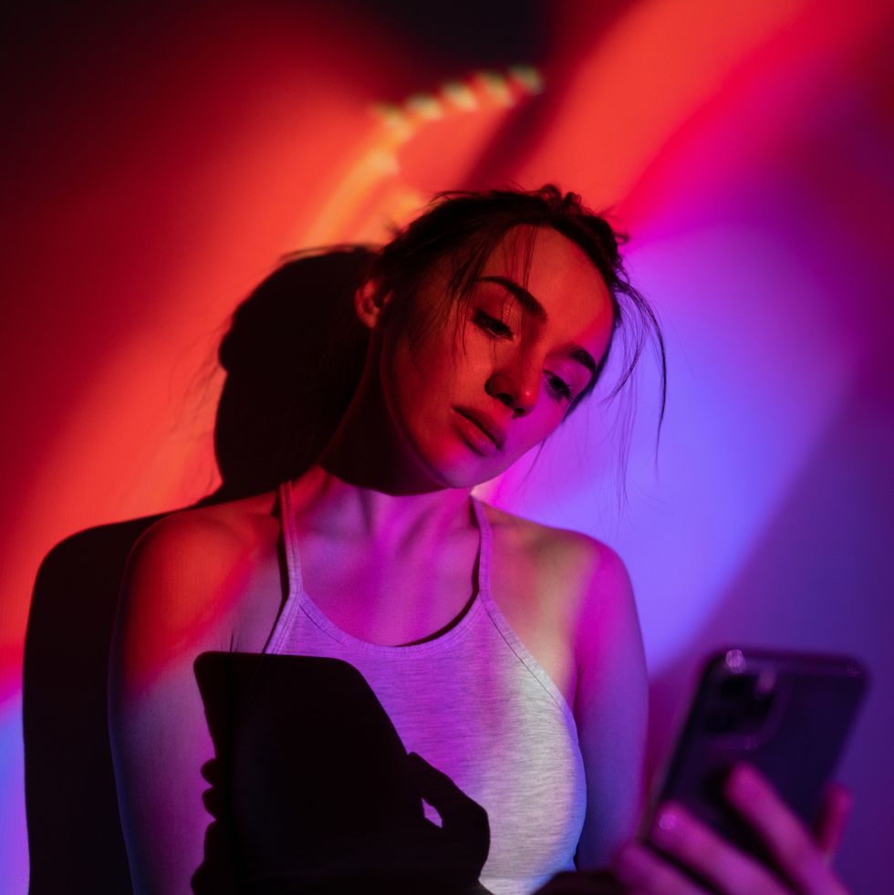 portrait of a young edgy woman posing and taking photos under the bright neon lights studio shot