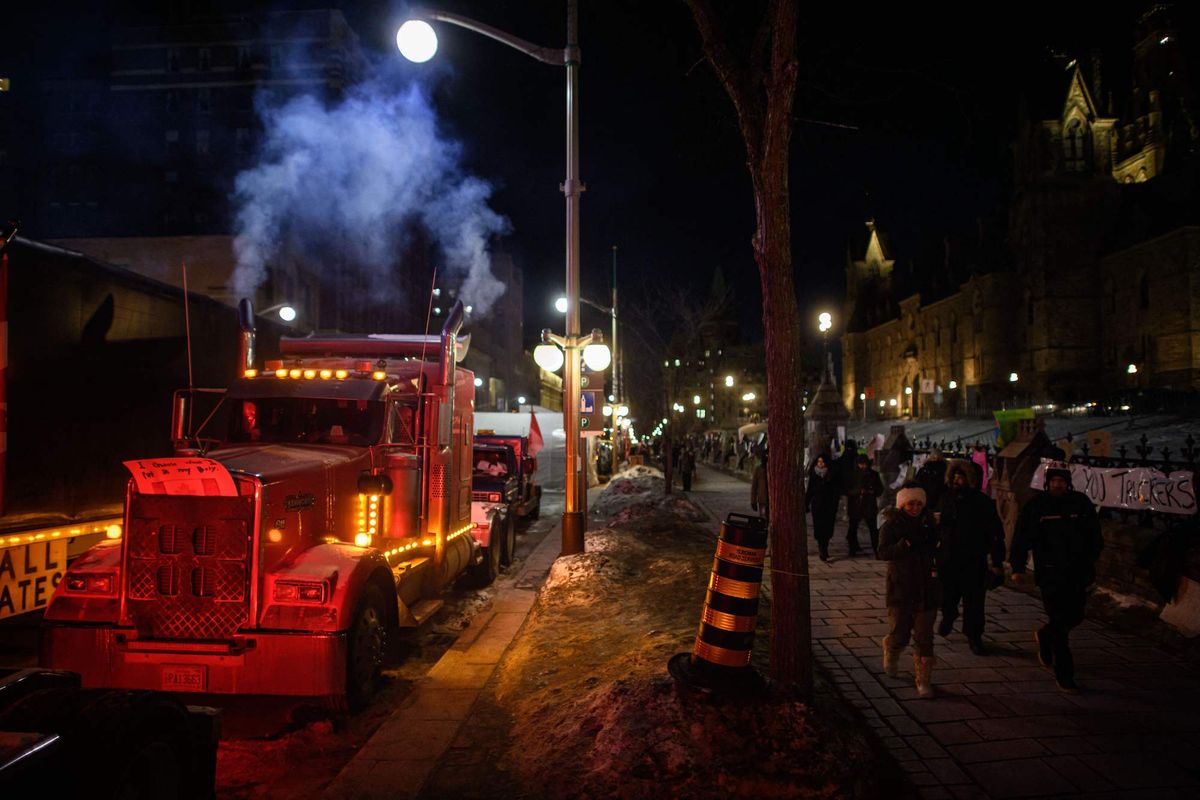 people walk past vehicles blocking a road during a protest by truck drivers over pandemic health rules and the trudeau government, outside the parliament of canada in ottawa on february 14, 2022   canadian prime minister justin trudeau on monday invoked rarely used emergency powers to bring an end to trucker led protests against covid health rules, after police arrested 11 people with a "cache of firearms" blocking a border crossing with the united states photo by ed jones  afp photo by ed jonesafp via getty images