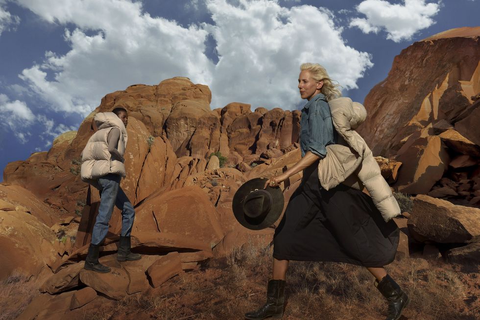 a woman holding a gun and a man standing on a rock