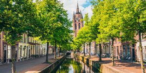 canal with leaning church tower in delft netherlands