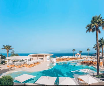 resort poolside scene with lounge chairs and palms