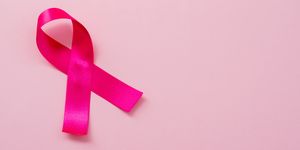 A pink ribbon on a pastel pink background. Breast cancer concept
