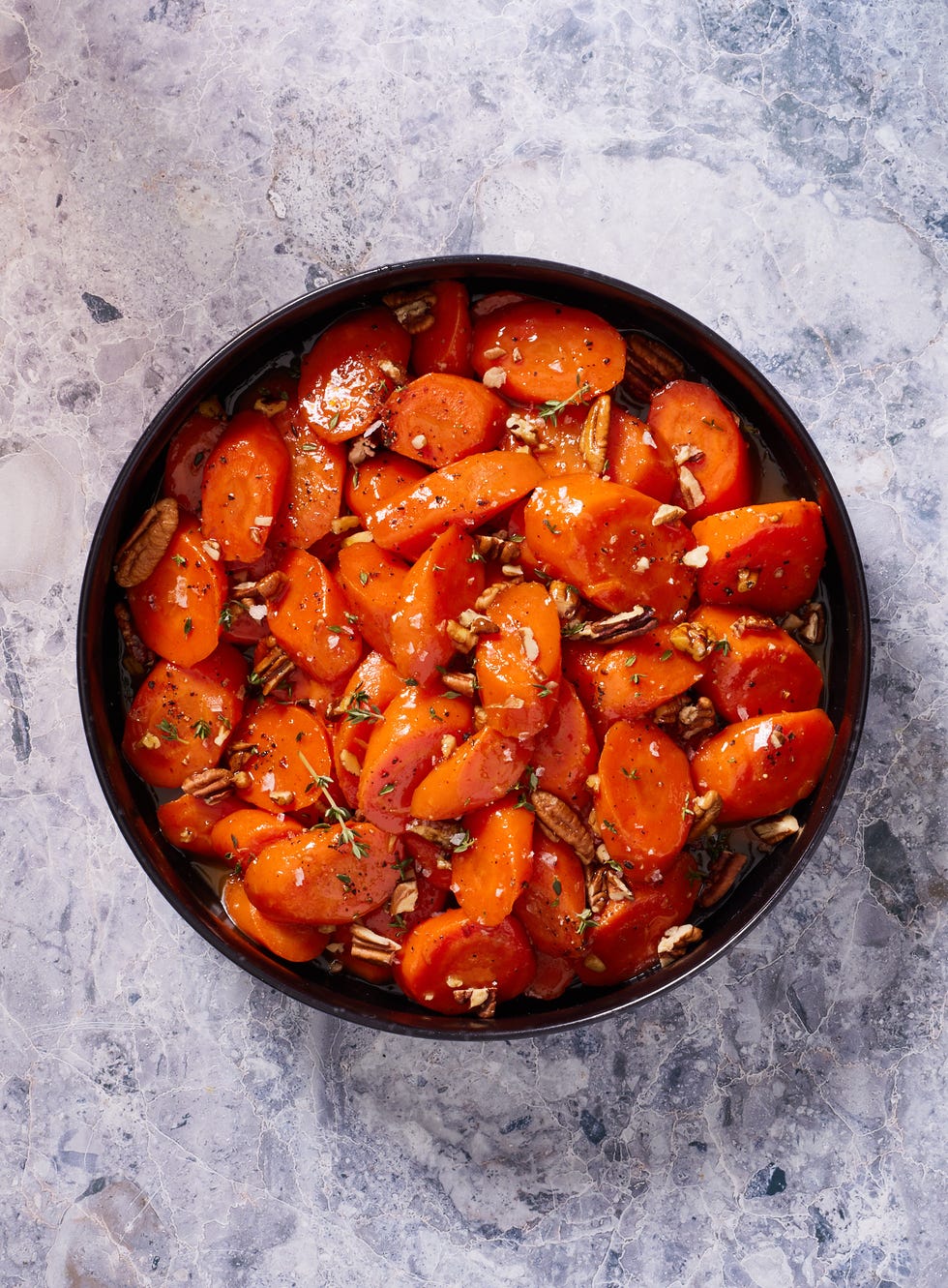 candied carrots with thyme and pecans in a black bowl