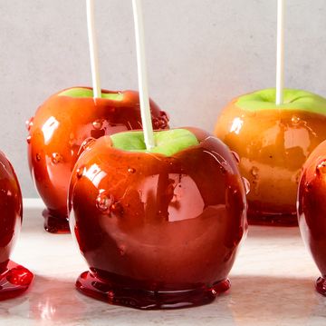 green apples with a red candy coating and a popsicle stick