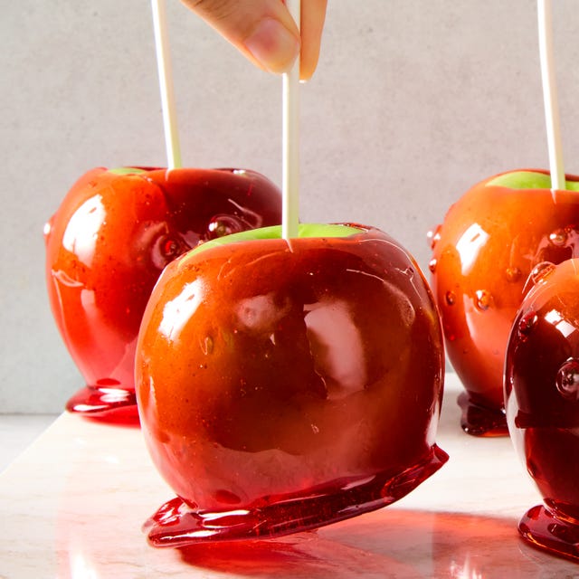 green apples with a red candy coating and a popsicle stick