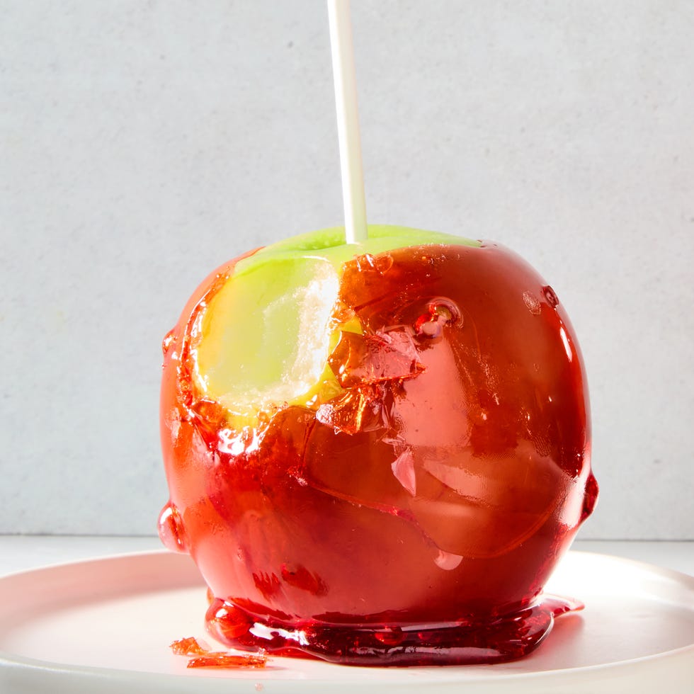 green apples with a red candy coating and a popsicle stick