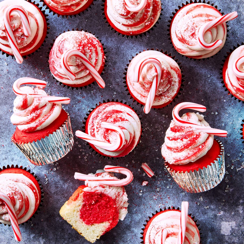 red cupcakes with icing topped with mini candy canes