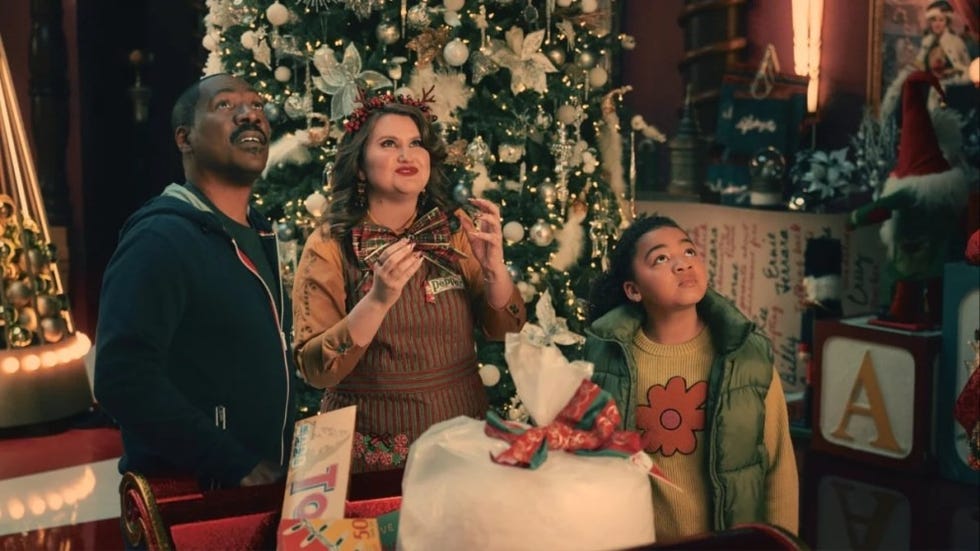 a dad and elf gaze up in awe at amazing decorations in a scene from candy cane lane