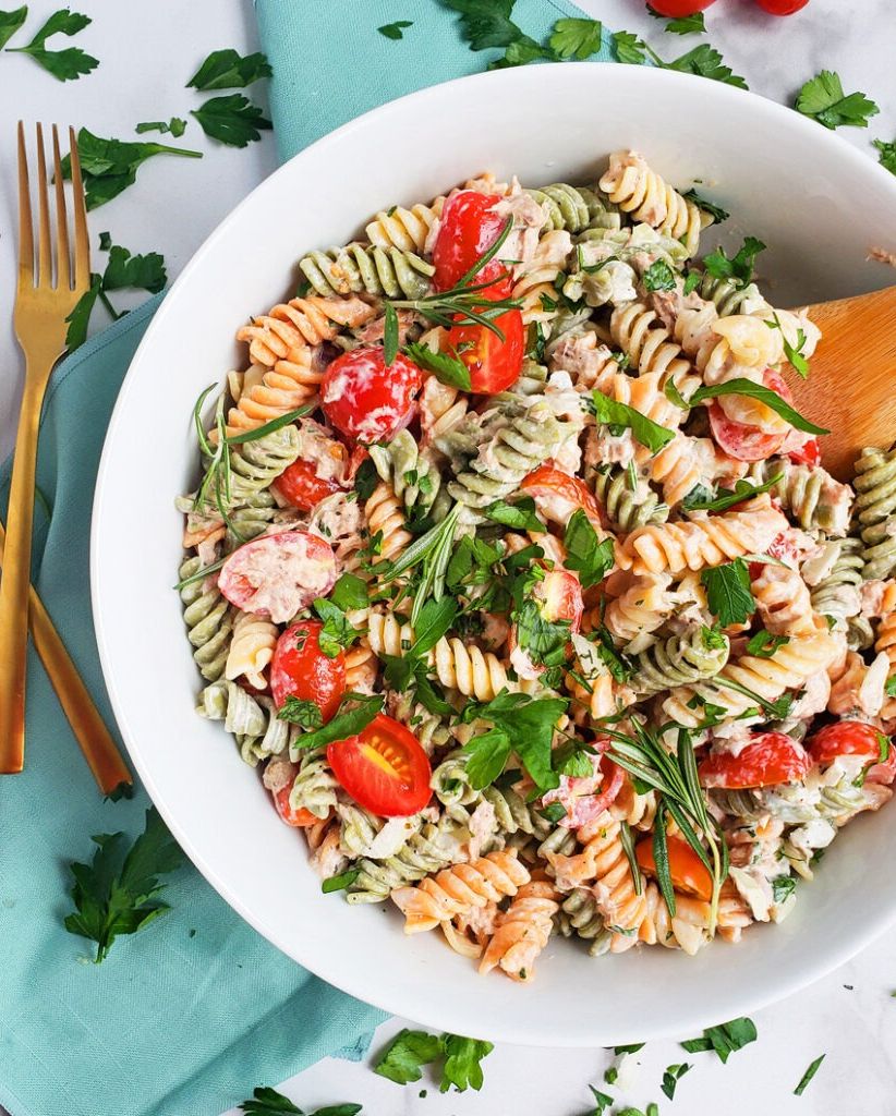creamy herb tuna pasta salad in a white bowl with a wooden serving spoon