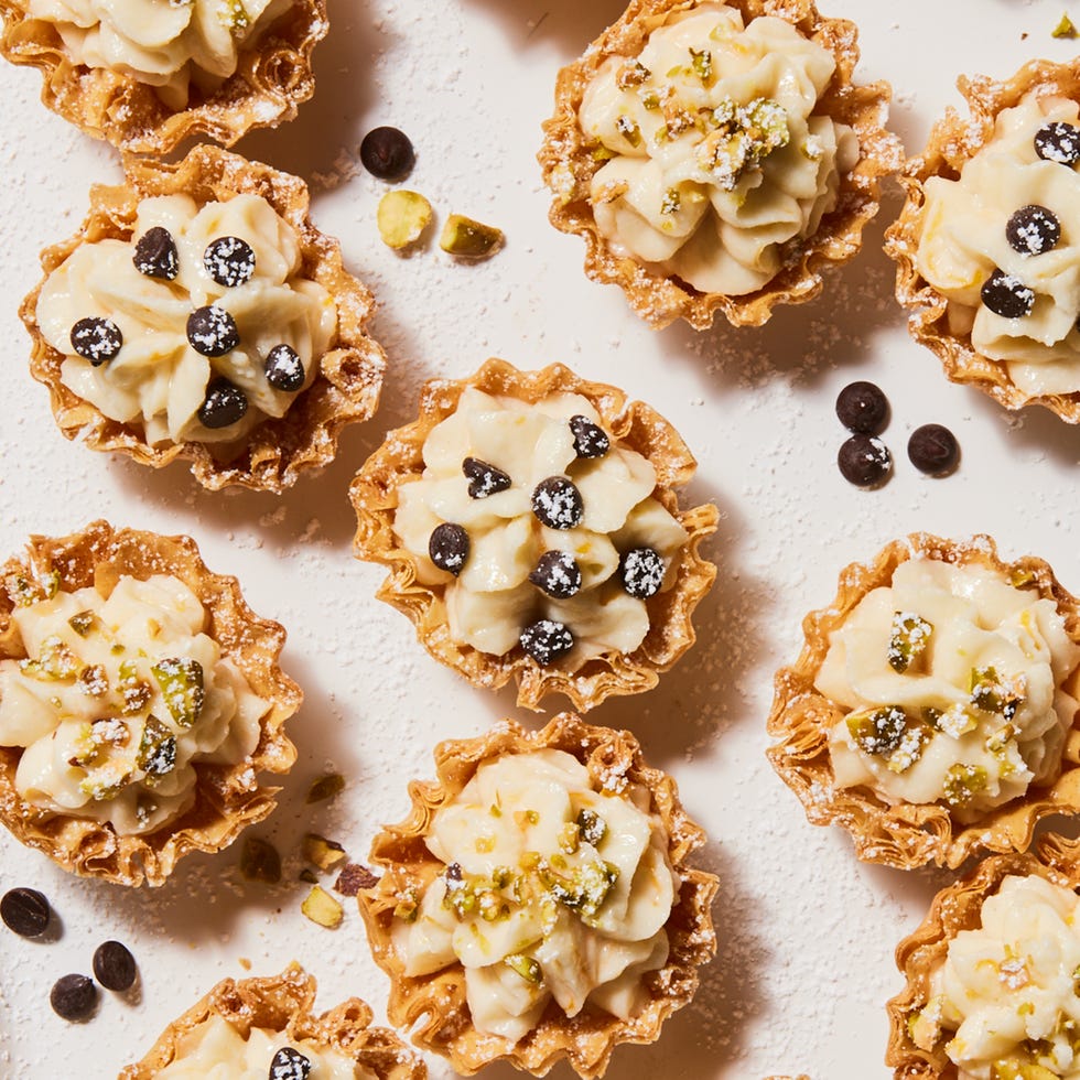 individual cannoli bites topped with chocolate chips, crushed pistachio and powdered sugar