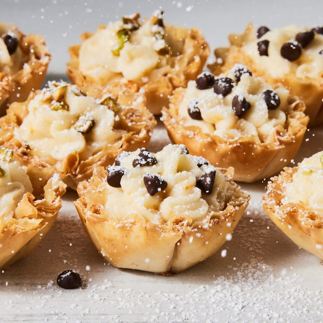 individual cannoli bites topped with chocolate chips, crushed pistachio and powdered sugar