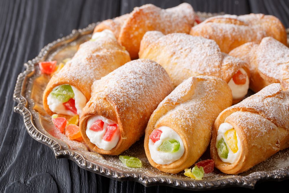 sweet cannoli stuffed with cheese cream and candied fruits close-up on a plate. horizontal