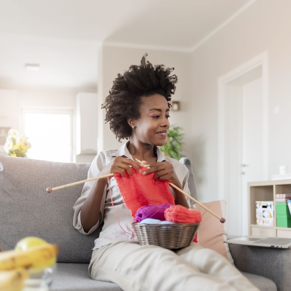 woman knitting on her couch