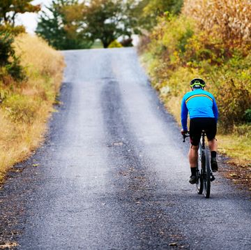 a person riding a bicycle on a gravel road
