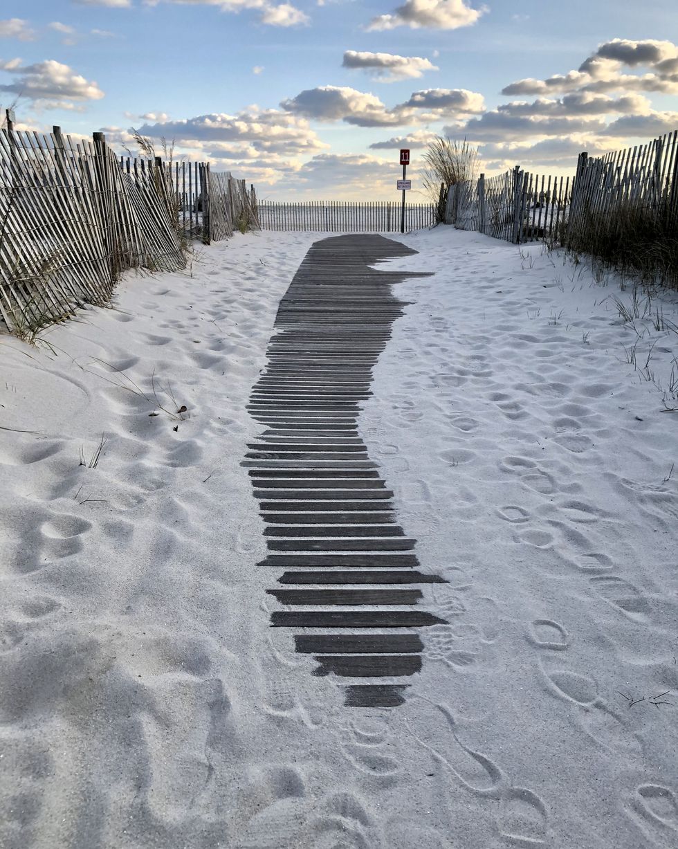 cape may at sunset with wooden walk lined by a fence over white sand