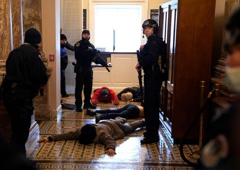 De politie van het Capitool houdt voor de deuren van de zaal van het Huis van Afgevaardigden demonstranten aan In het Capitool zou een vrouw zijn neergeschoten