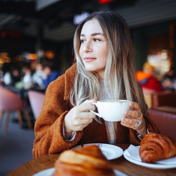 cappuccino and frensh croissant in the cafe a woman eats her breakfast