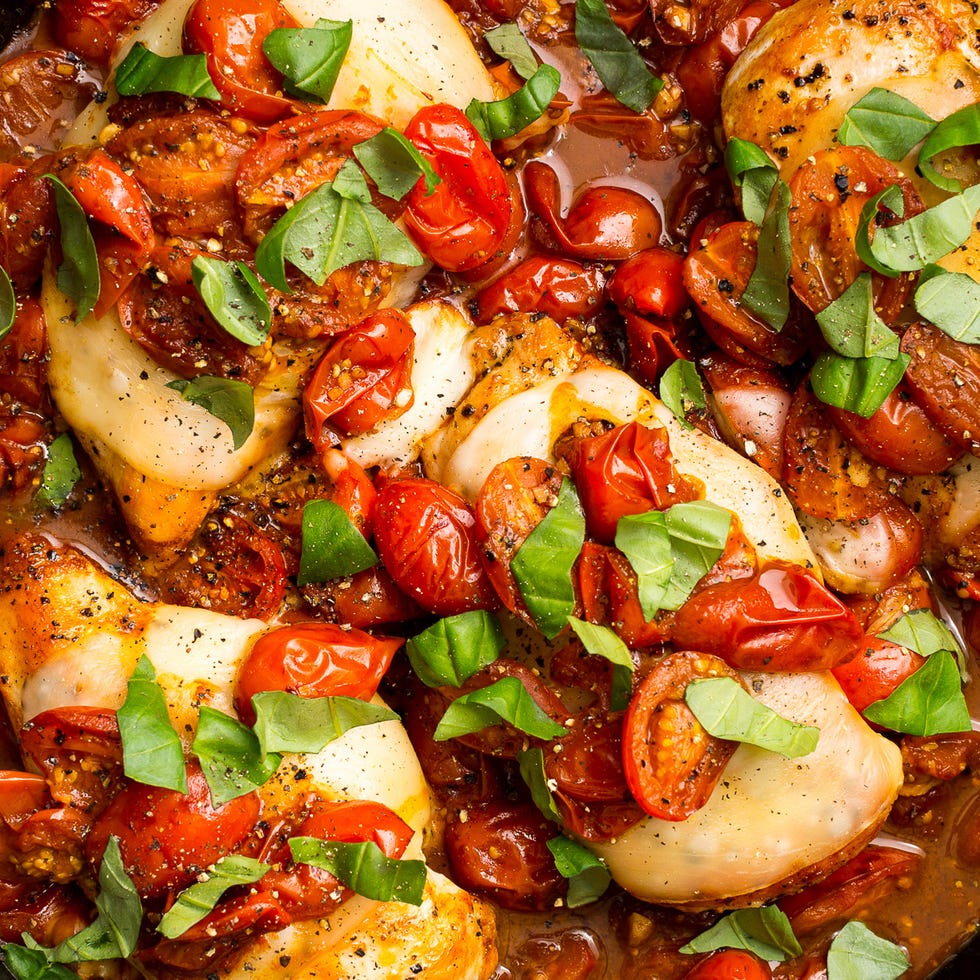 chicken breasts cooked in a skillet with cherry tomatoes, mozzarella, and basil