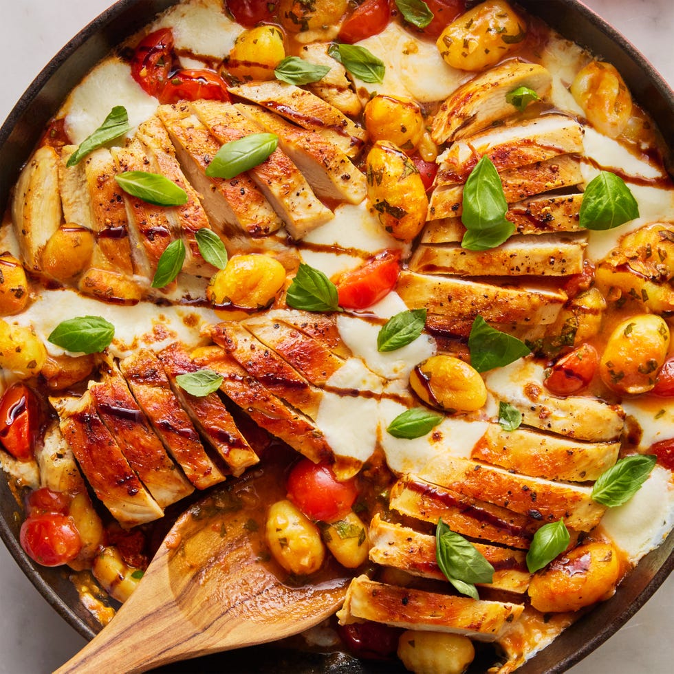 chicken with gnocchi, tomatoes, and cheese in a red skillet