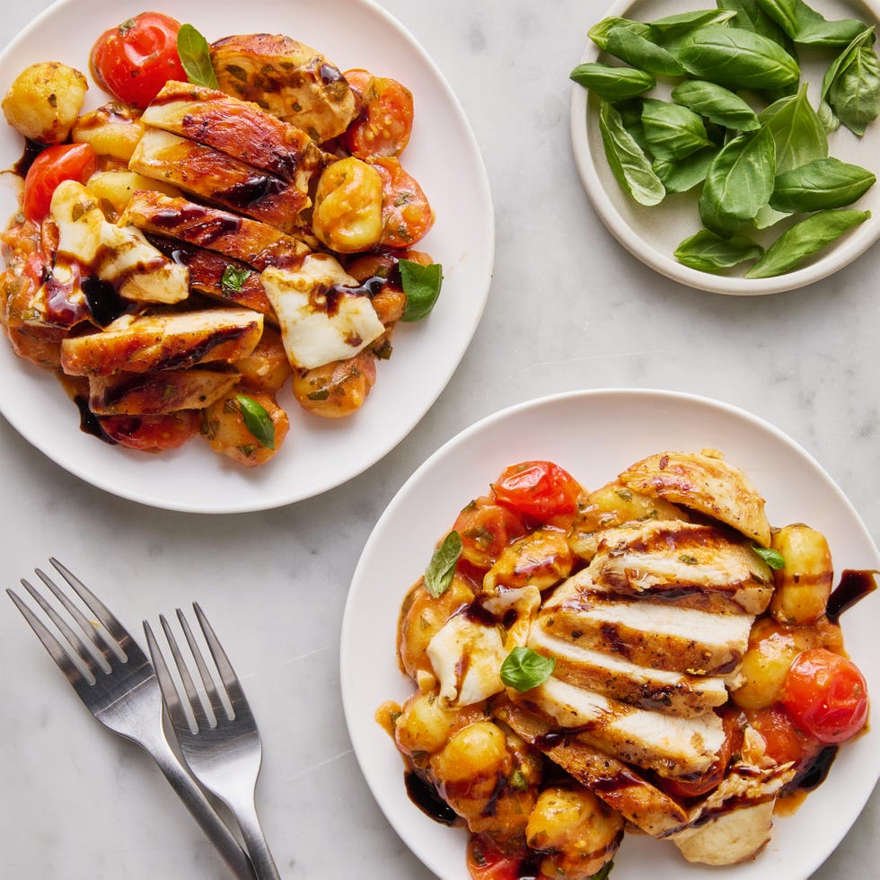 chicken with gnocchi, tomatoes, and cheese in a red skillet