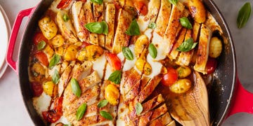 chicken with gnocchi, tomatoes, and cheese in a red skillet