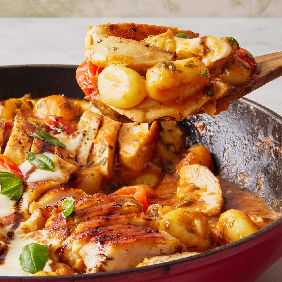 chicken with gnocchi, tomatoes, and cheese in a red skillet