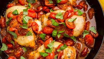 chicken breasts cooked in a skillet with cherry tomatoes, mozzarella, and basil