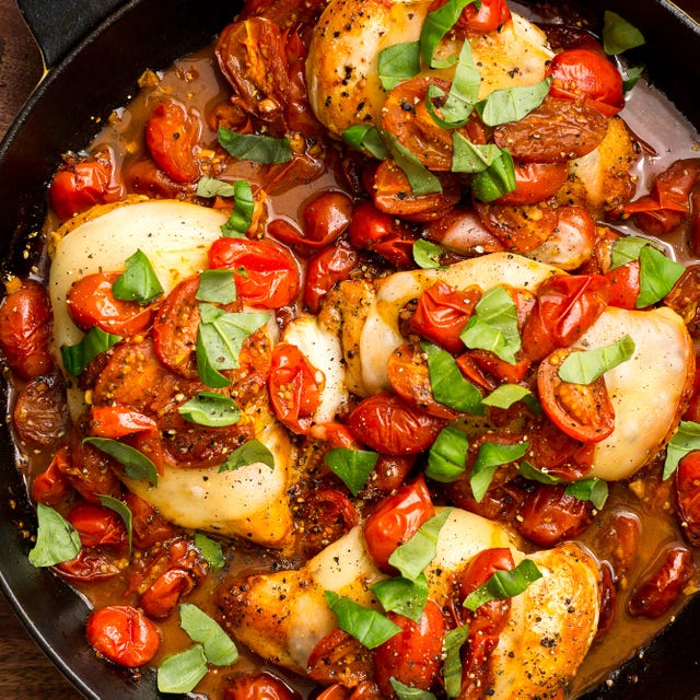 chicken breasts cooked in a skillet with cherry tomatoes, mozzarella, and basil