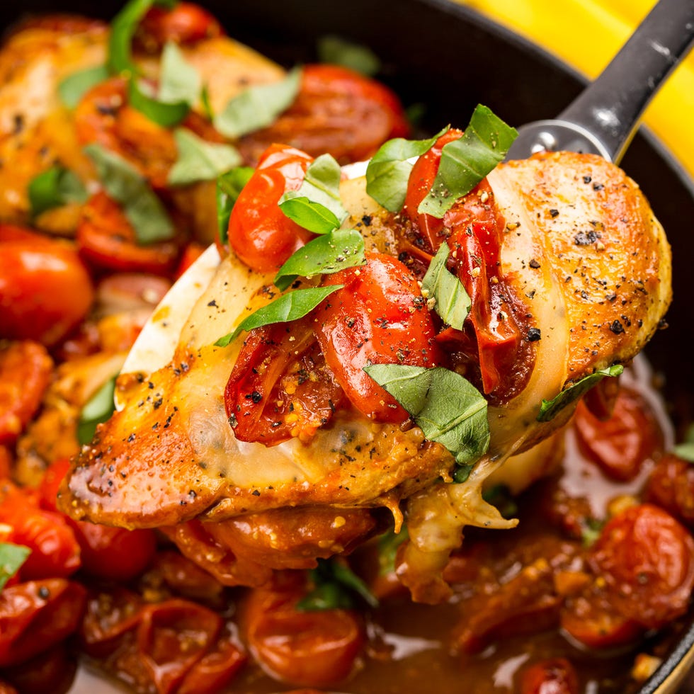 chicken breasts cooked in a skillet with cherry tomatoes, mozzarella, and basil