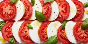 sliced tomatoes, mozzarella, and basil on a plate drizzled with olive oil