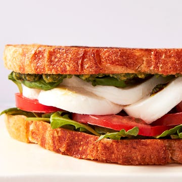 toasted bread layered with mozzarella, tomato slices, basil, arugula, pesto, and balsamic