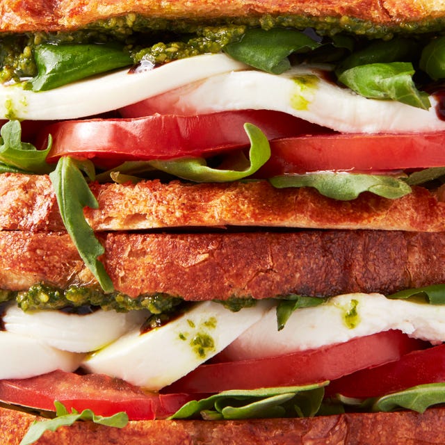 toasted bread layered with mozzarella, tomato slices, basil, arugula, pesto, and balsamic
