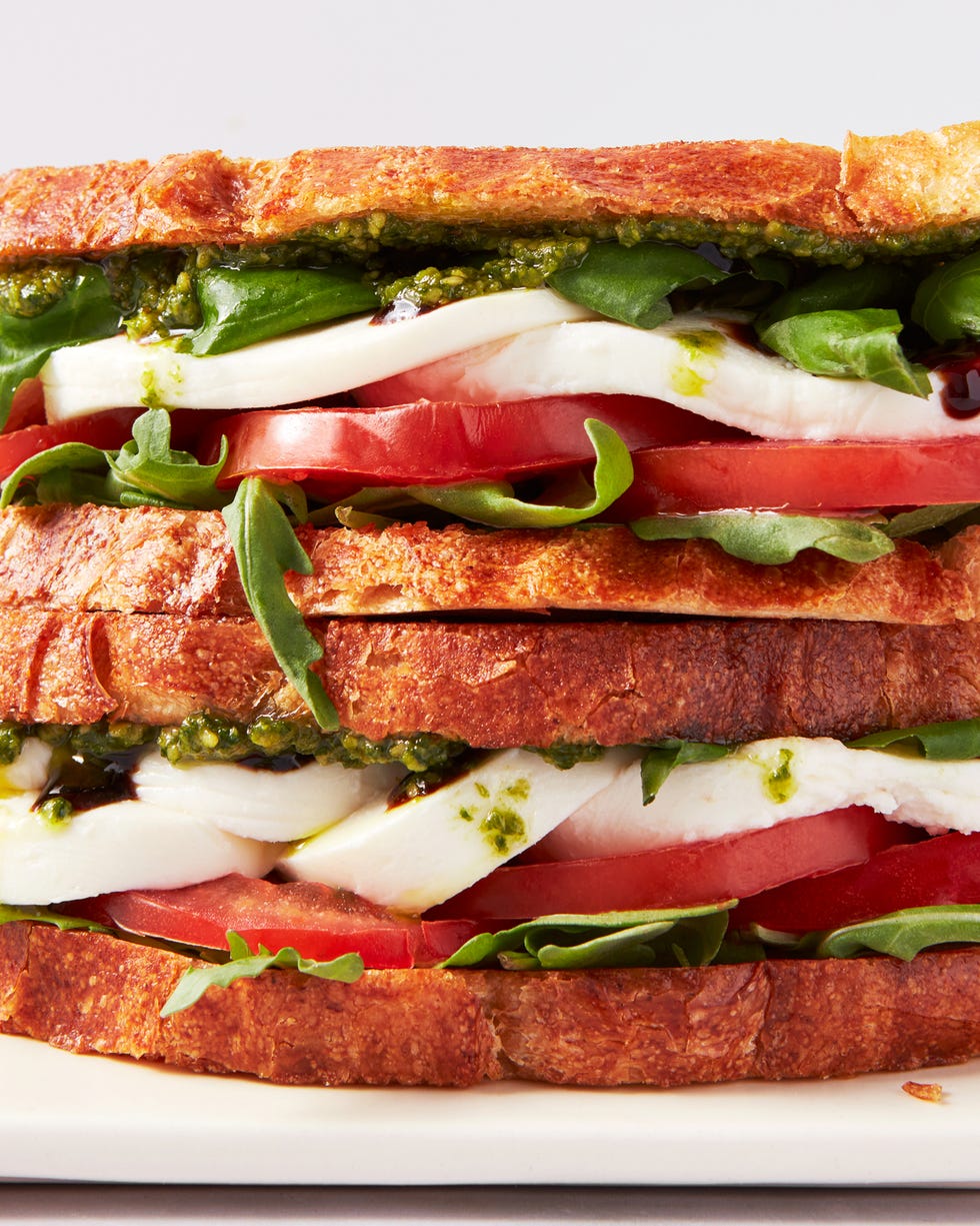 toasted bread layered with mozzarella, tomato slices, basil, arugula, pesto, and balsamic