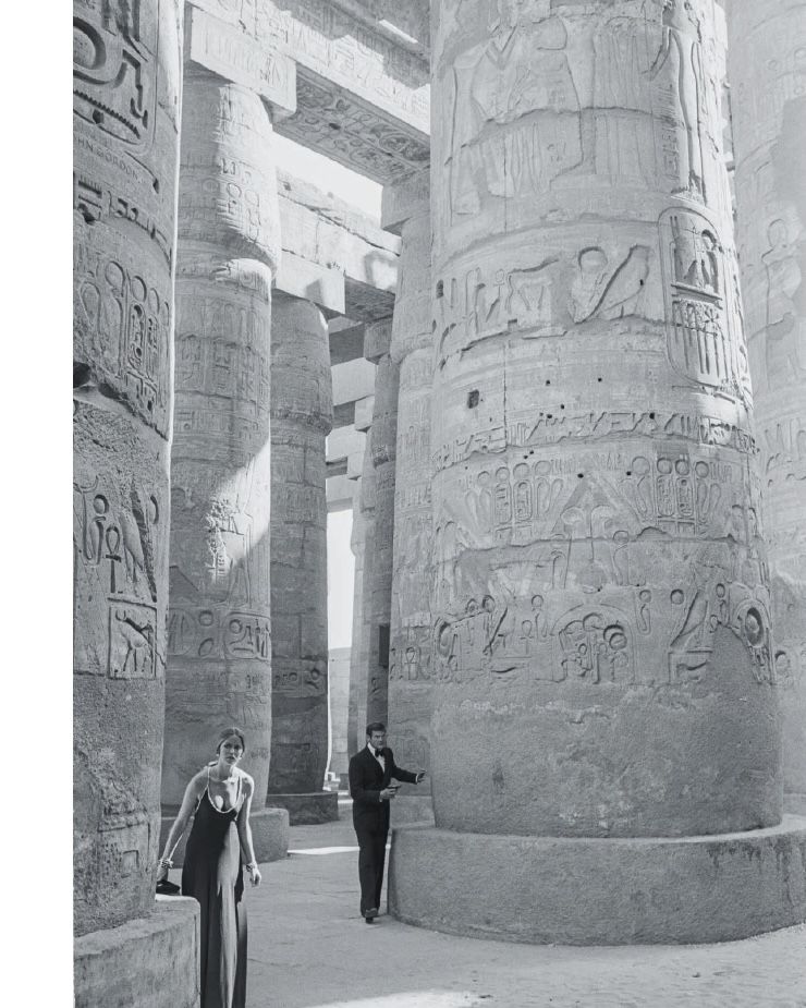 a man and woman standing in front of a stone pillar