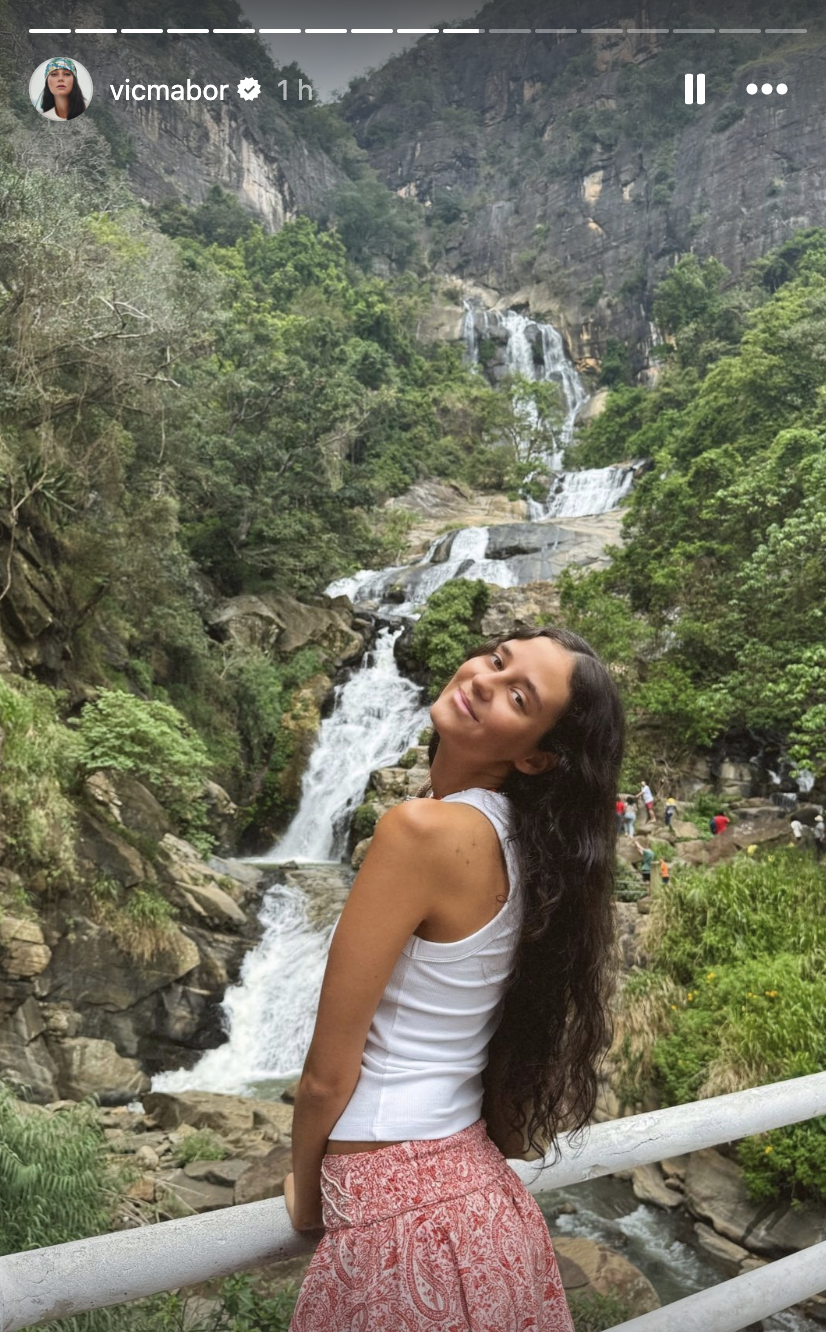 a woman posing for a picture next to a waterfall