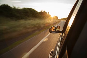Car driving along road, reflection in wing mirror