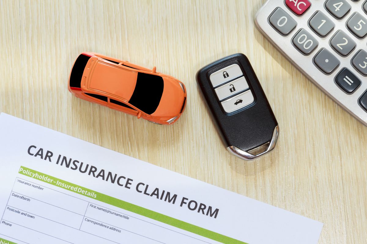 Car Insurance Claim Form With Toy And Key On Table