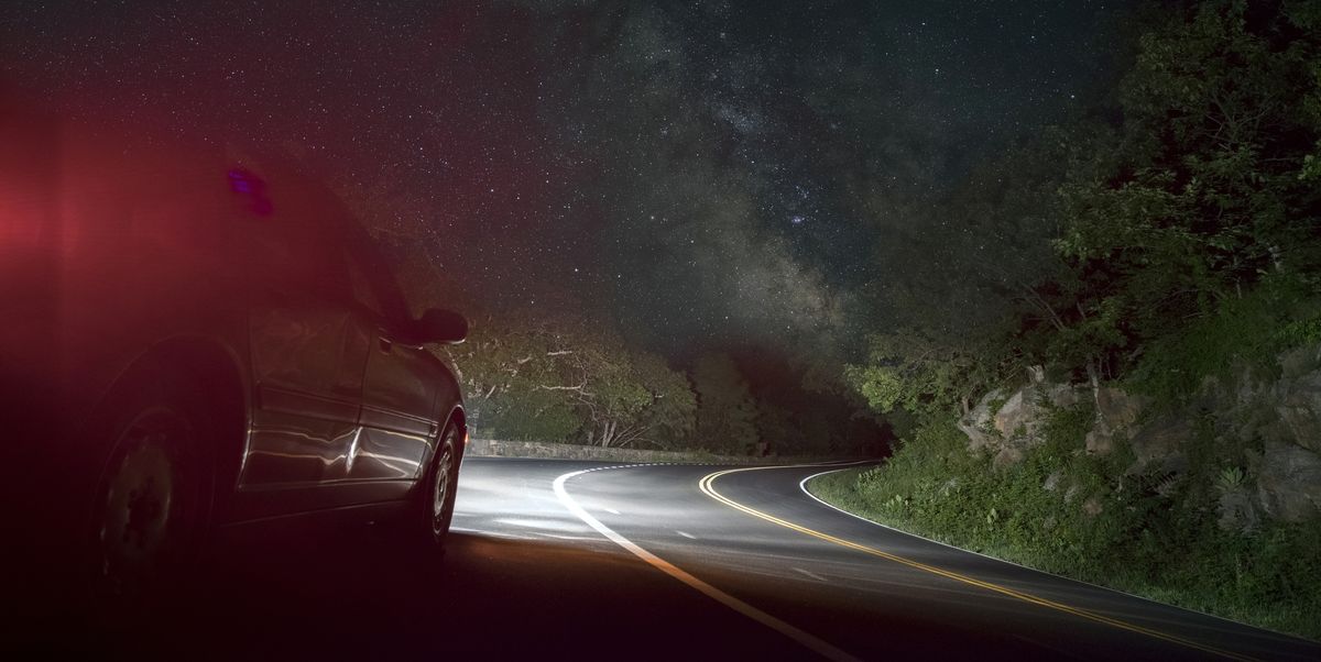 Car on winding road under starry sky
