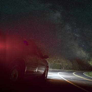 Car on winding road under starry sky