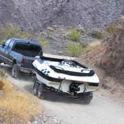 a car towing a boat through the dirt road