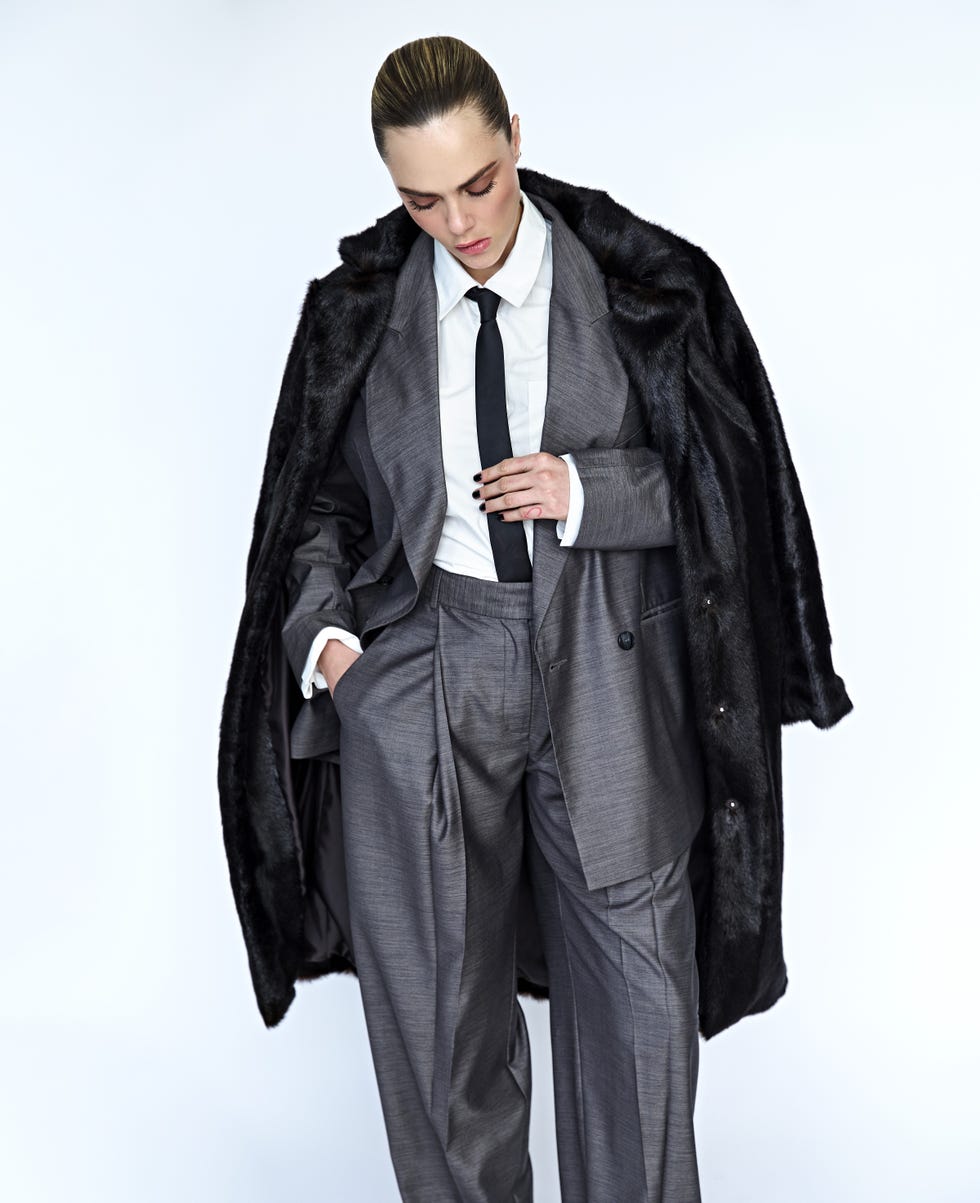 a person dressed in a sharp gray suit with a black fur coat