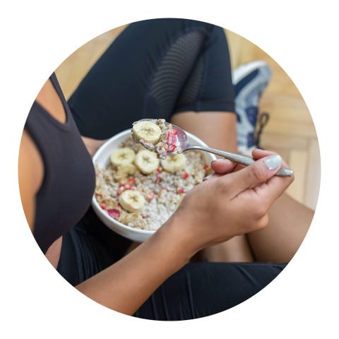 woman eating a bowl of oatmeal with fruit in workout clothes
