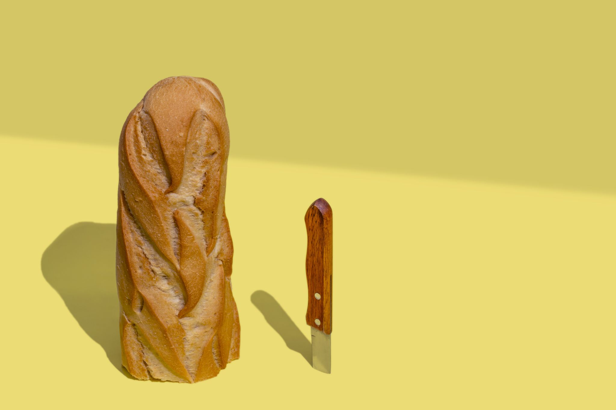 half loaf of bread and a knife on yellow background