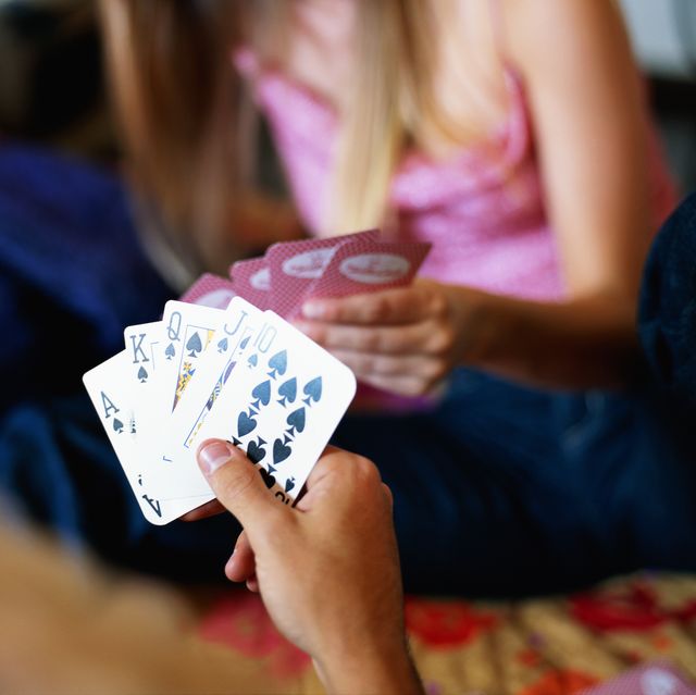 a man holding a stack of cards, focus on the cards, woman with cards is out of focus in front of him