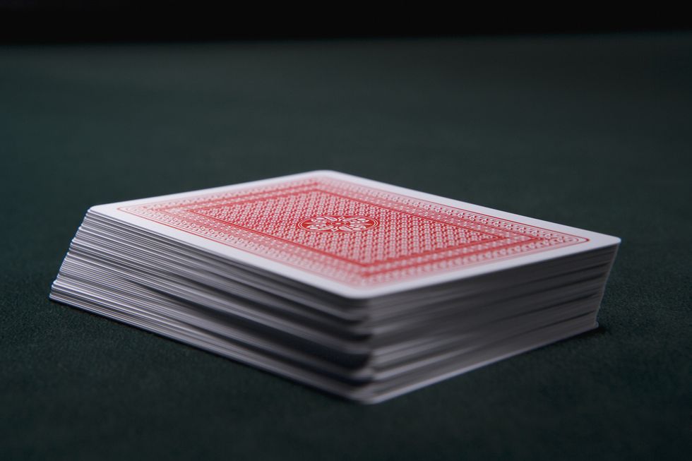 deck of red and white playing cards face down on a black background