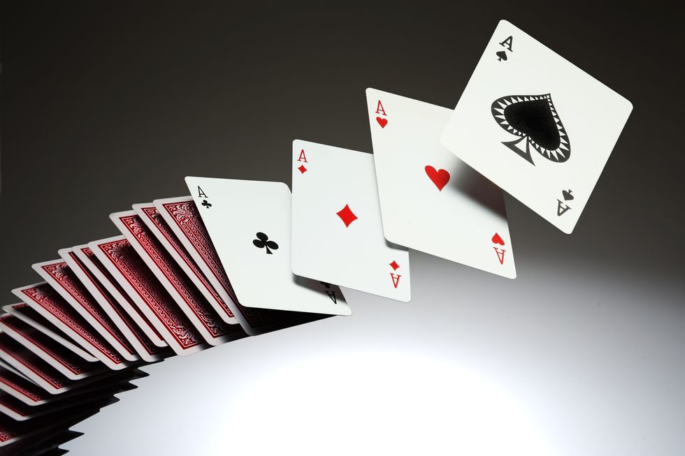 a deck of cards spread out through the air with the four aces turned over with faces showing and the rest face down