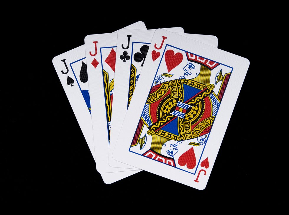 four jack playing cards fanned out against a black background