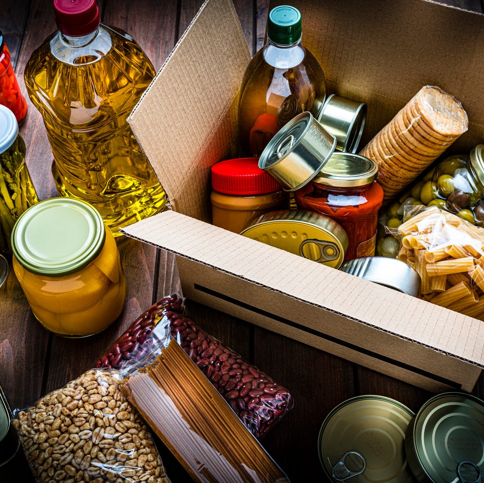Cardboard box filled with nonperishable foods on wooden table. High angle view. cardboard box filled with nonperishable foods on wooden table